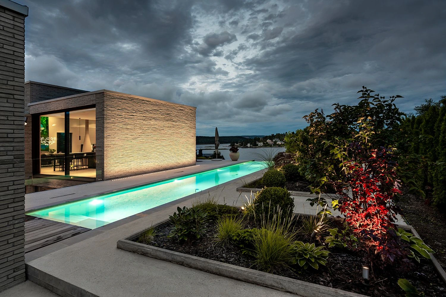 Iluminación exterior de una casa con piscina, fachada y vegetación iluminadas